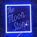 A neon sign that reads 'The Moon Stone' in a square frame with a blue background.